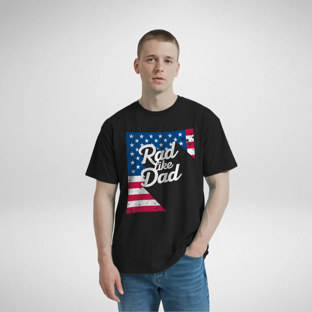 Man wearing a black 'Rad Like Dad' t-shirt with a vintage American flag design, casually posing with hands in his pockets.