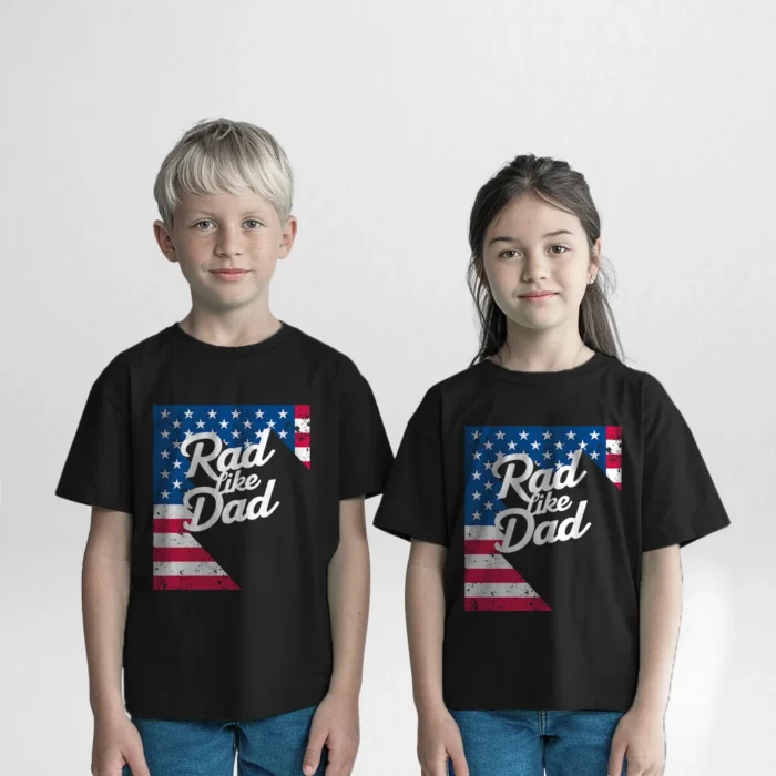 Two children, a boy and a girl, wearing matching black 'Rad Like Dad' t-shirts with a distressed American flag design, standing side by side, smiling for the camera.