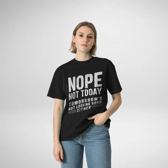 Woman posing in a black t-shirt featuring the text 'NOPE NOT TODAY, TOMORROW'S NOT LOOKING GOOD EITHER,' with her hand in the pocket of her jeans."